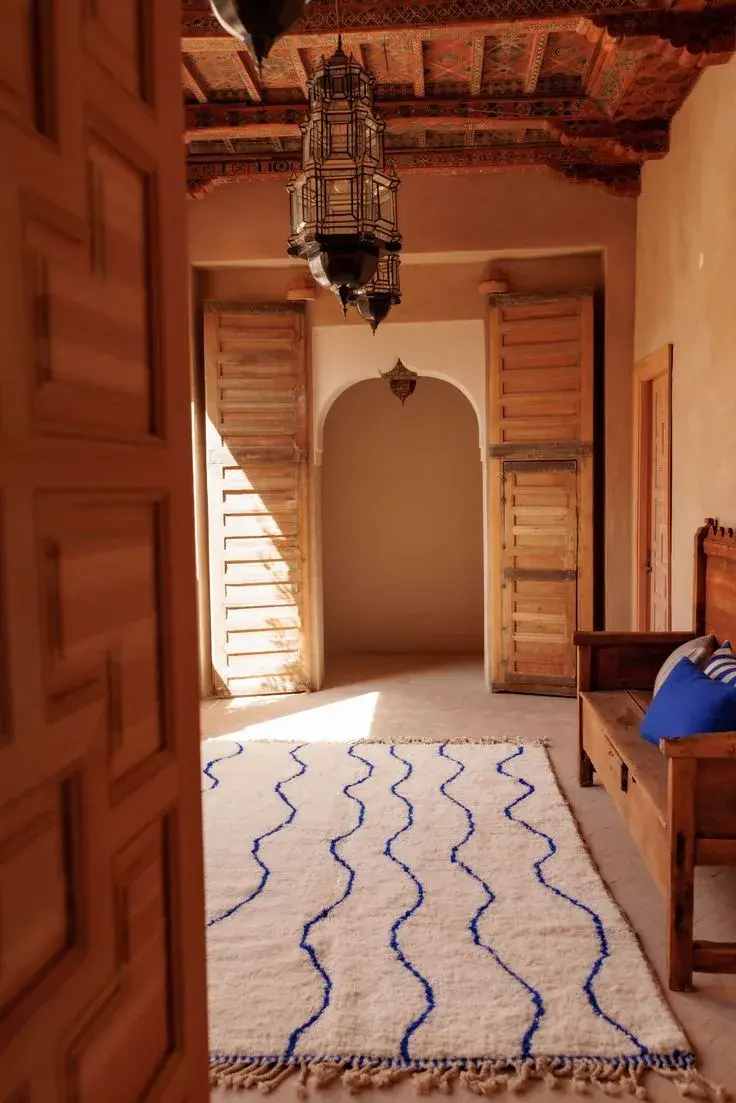 A cream runner with blue wave lines on the floor of a sunlit hallway
