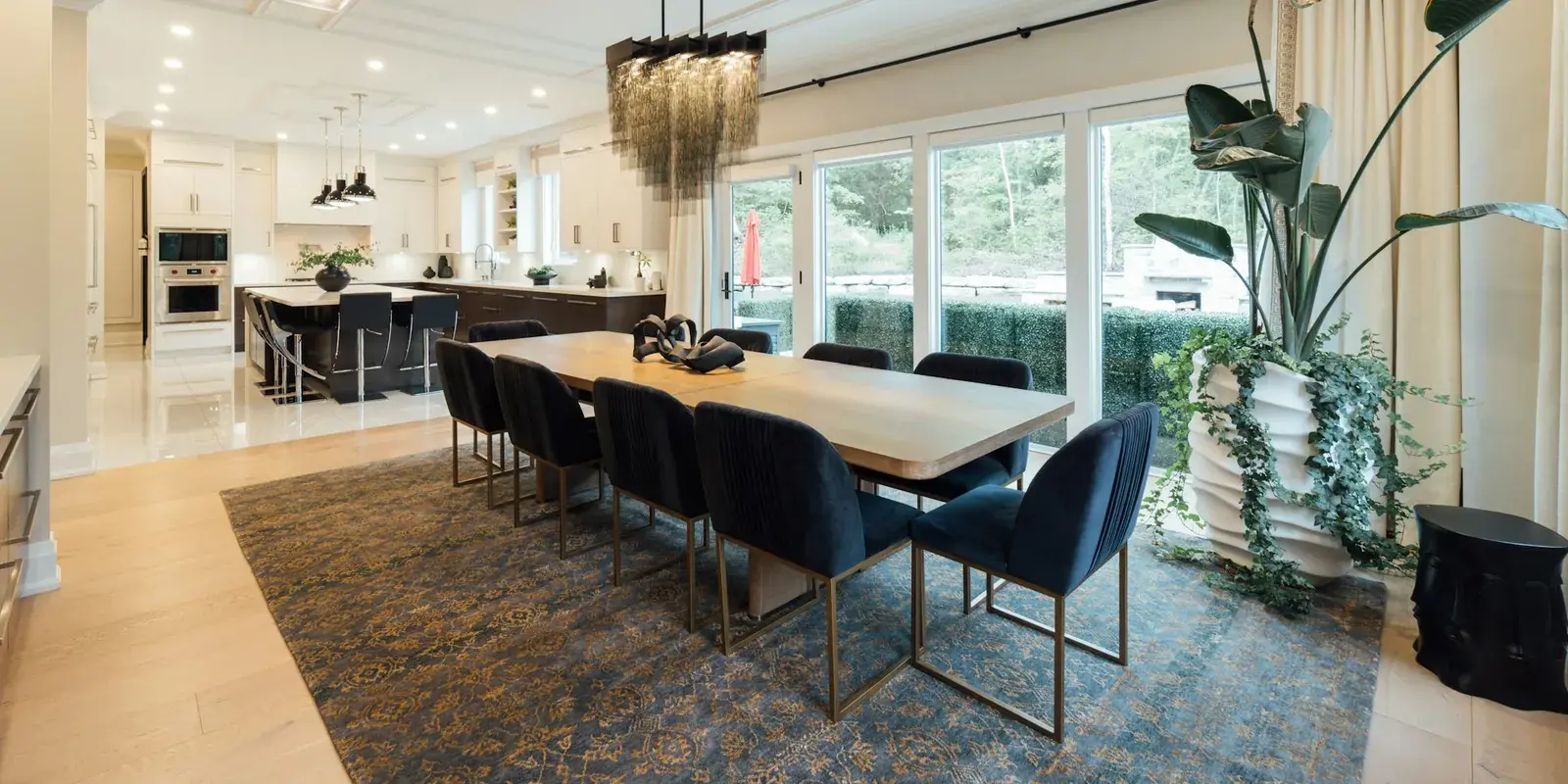 A large dining room with navy chairs and a long table set on a blue patterned rug