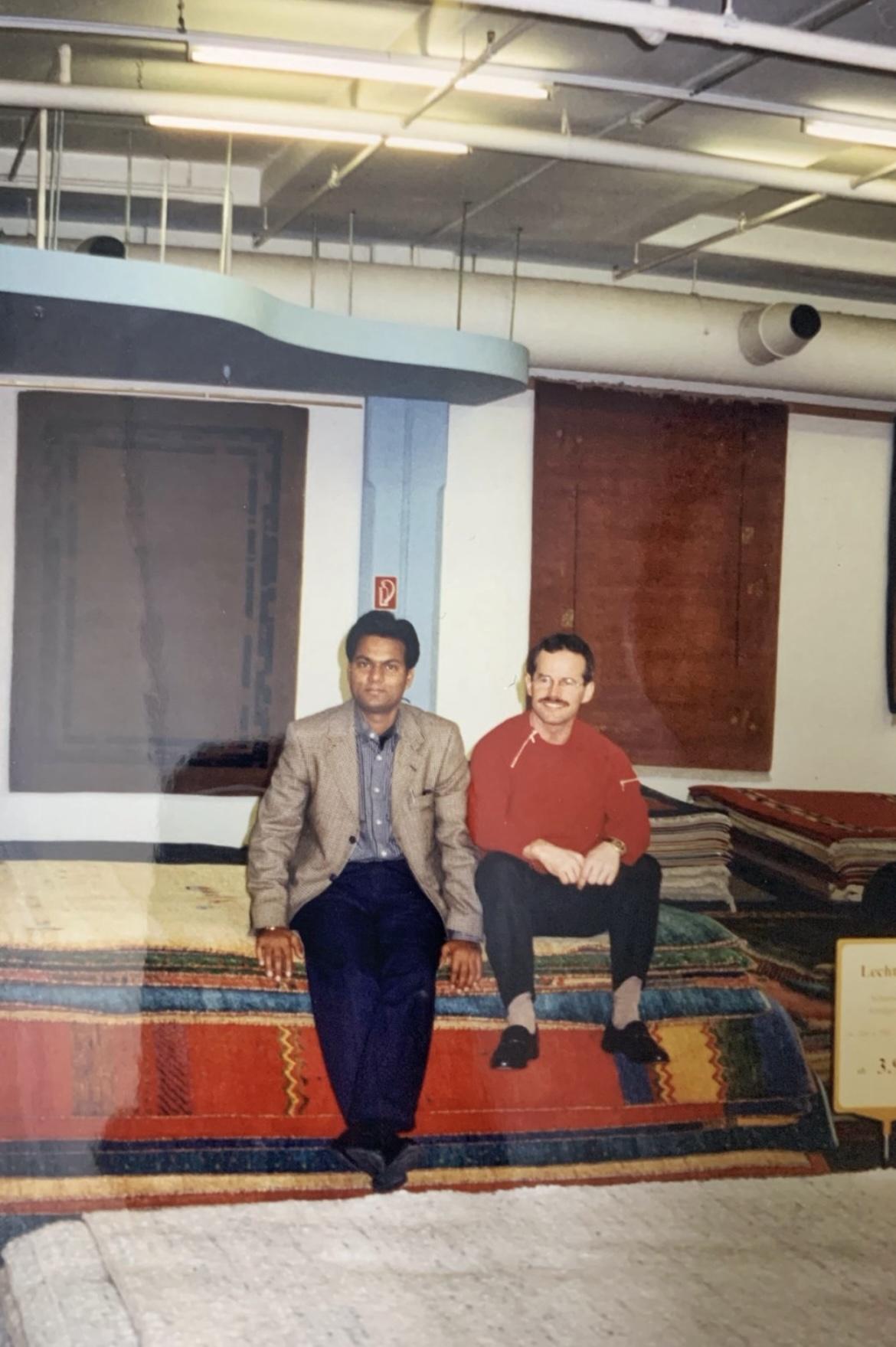 A visiting buyer and his host seated on rugs in a Bhadohi showroom, from the family archive