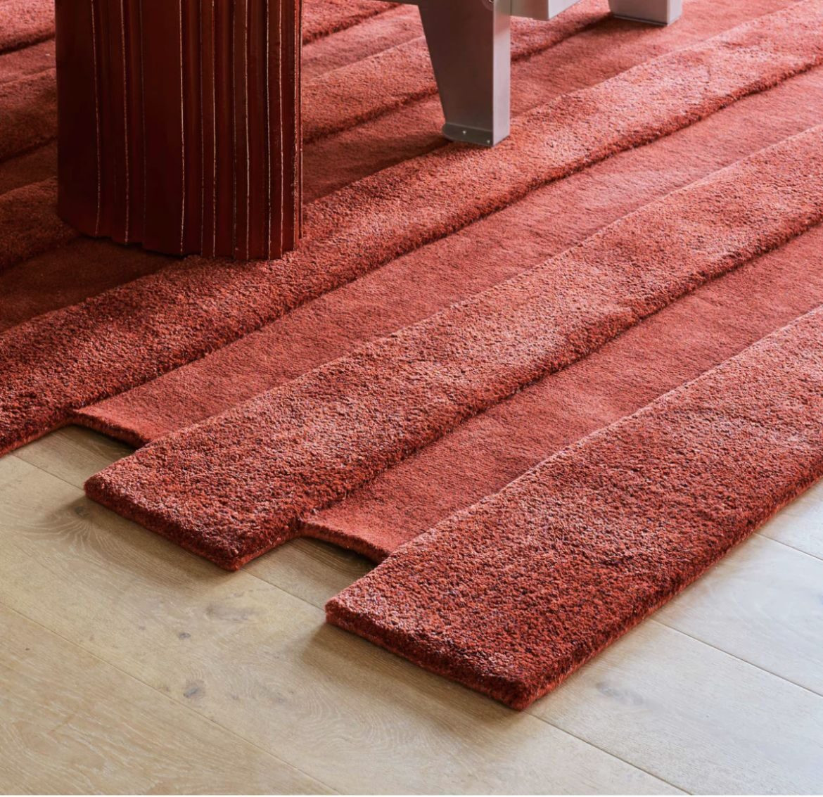 Hand-woven rugs in deep reds, laid one over another on a pale floor