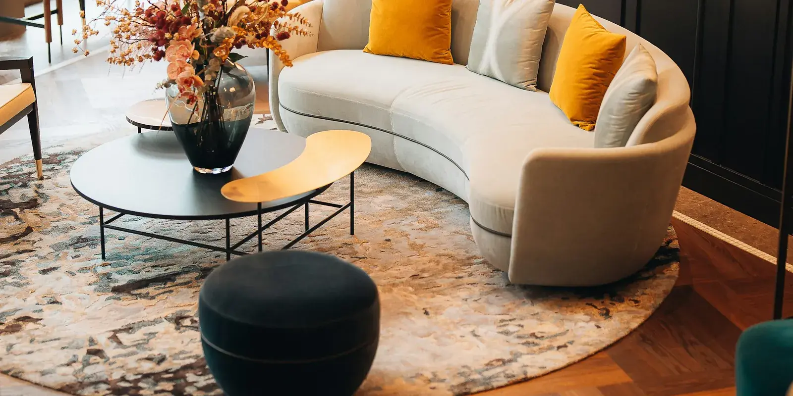 A hotel lounge with a curved cream sofa, black coffee table and a patterned round rug