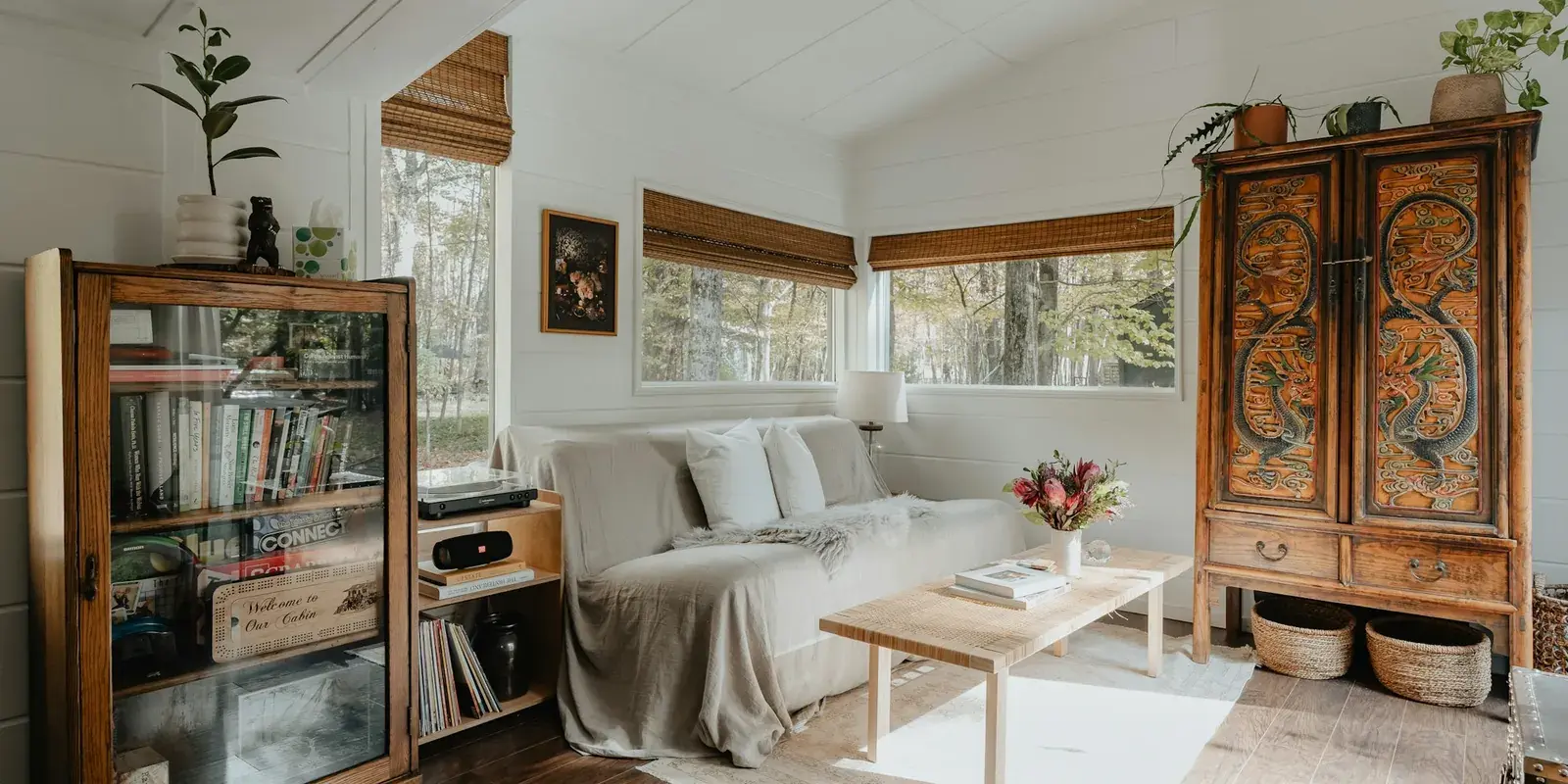 A bright white living room with a linen-covered sofa, a pale coffee table and a rug on a wood floor
